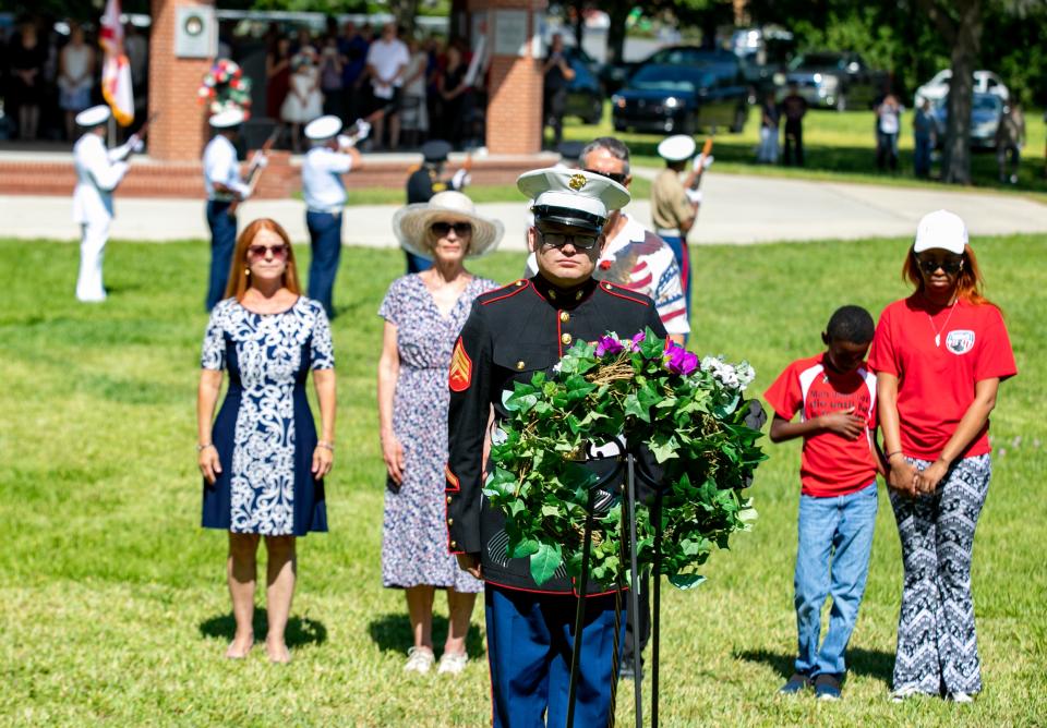 Marine Sgt. Ronald Shaffer stands with, from left, Anne Crowder, Sigrid Paddock, Joel Harrison, Jayson Sims, and his mom, Shakeli Sims, as they present the memorial wreath on Monday during the Memorial Day Remembrance Ceremony at the Ocala-Marion County Veterans Memorial Park in Ocala.