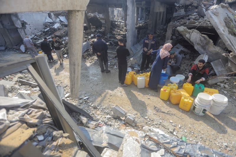Palestinians collect water from a house destroyed by an Israeli strike, in Jabalia refugee camp in the northern Gaza Strip
