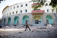 A police officer walks past a damaged building after an earthquake in Tirana