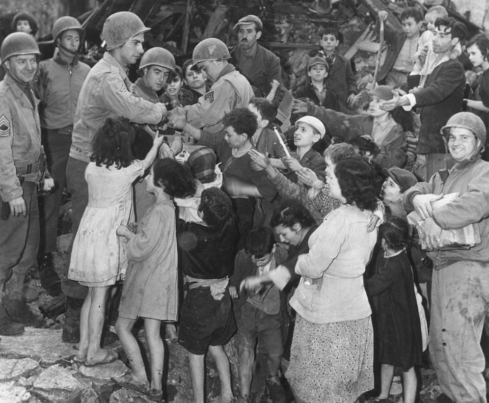 American GIs provide some Christmas cheer for the children of an Italian village demolished by the retreating German army, donating gifts from their own stores, in 1945.