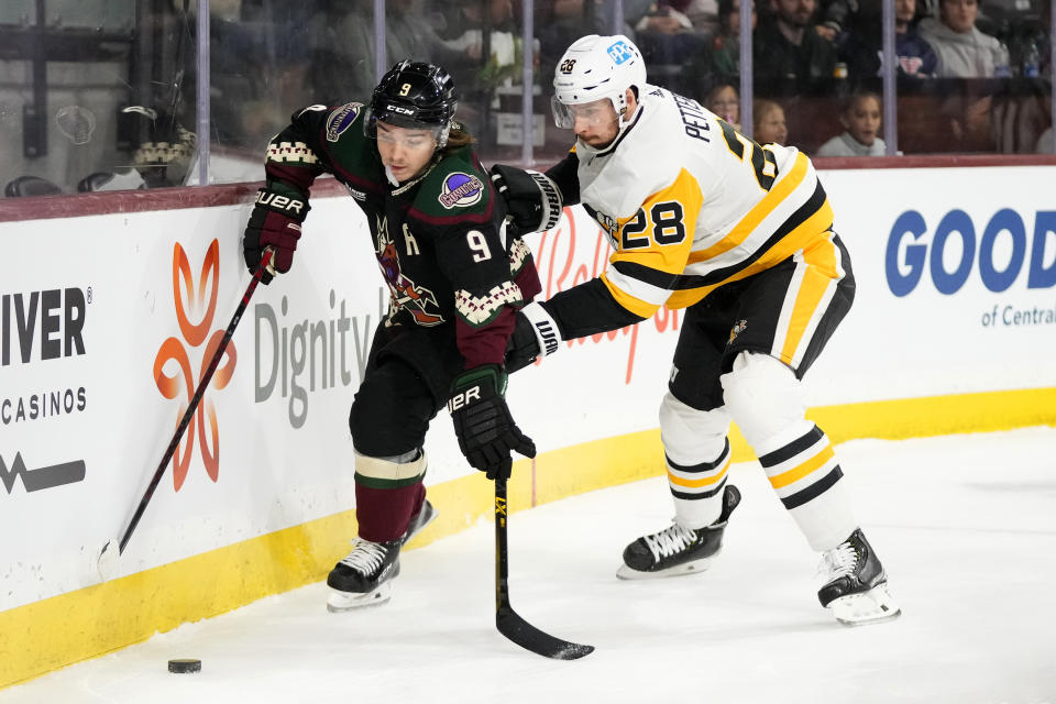 Arizona Coyotes right wing Clayton Keller (9) tries to keep the puck away from Pittsburgh Penguins defenseman Marcus Pettersson (28) during the first period of an NHL hockey game in Tempe, Ariz., Sunday, Jan. 8, 2023. (AP Photo/Ross D. Franklin)