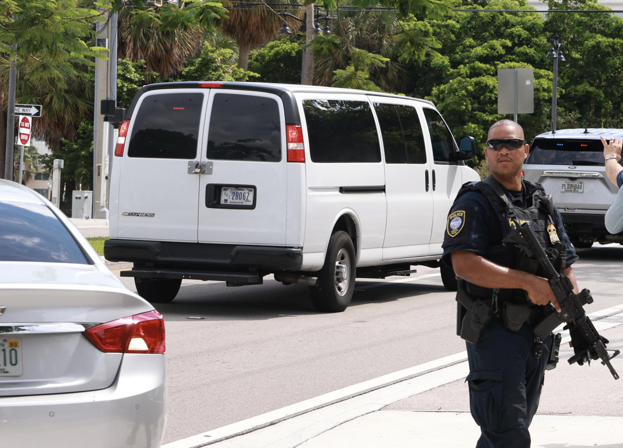 A van carrying suspect Ryan Wesley Routh leaves the courthouse as an armed officer stands watch nearby.