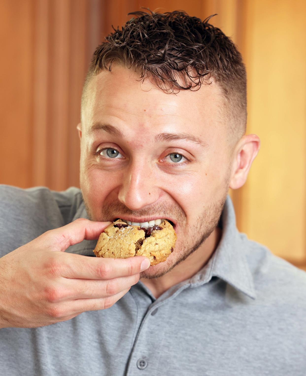Daniel Gavigan of Middleboro, the owner of Danny's Dozens, eats one of his creations on Saturday, May 4, 2024. His cookie flavors include, "Everything But Candles," "My Name Is Earl" and "Browned Buttered Bourbon Pecan."