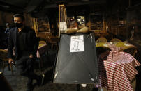 A drawing of a cross is placed outside an empty restaurant in Rome's Campo de' Fiori square, a popular evening spot of restaurants and pubs, to protest against the closing of the square, Friday, Oct. 23, 2020. (AP Photo/Alessandra Tarantino)