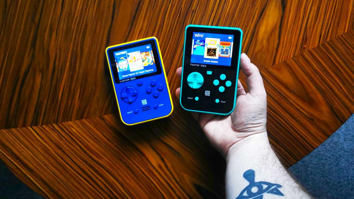  Capcom and Taito Super Pocket handhelds on woodgrain table. 