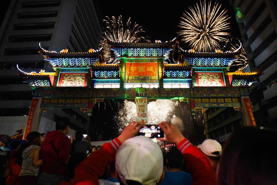 A man films the scene with his mobile phone as fireworks illuminate the sky above the Chinatown friendship arch, the largest in the world, located in Binondo district, Manilas Chinatown, on Chinese New Years Eve, in Manila, Philippines