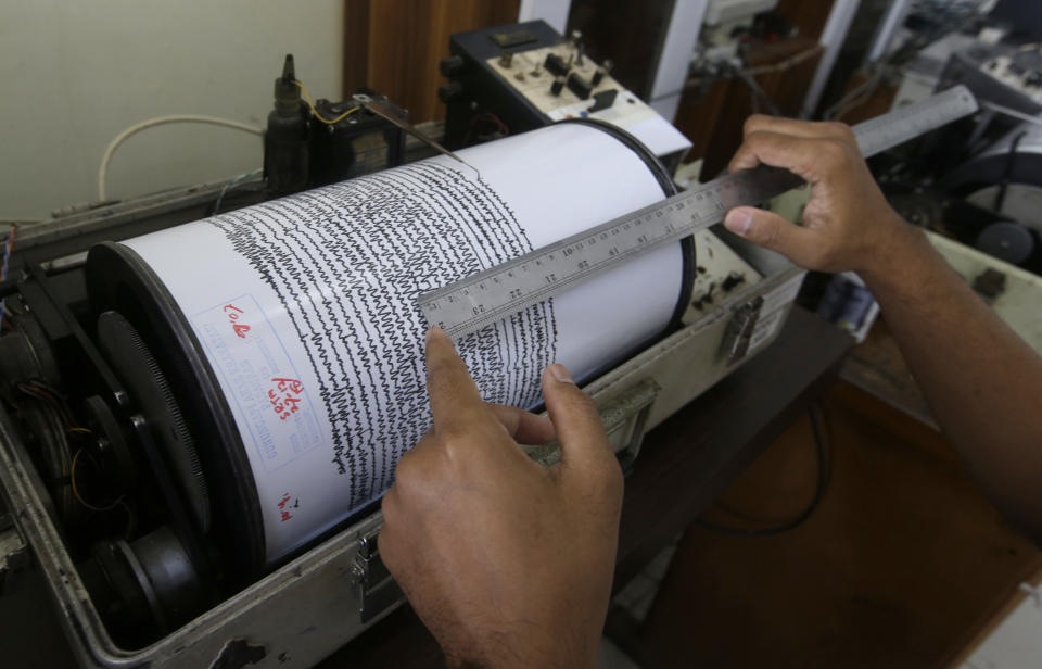 An official looks a seismograph at an observation post near a recent volcanic eruption in Carita, Indonesia, Thursday, Dec. 27, 2018. Indonesia has widened the no-go zone around an island volcano that triggered a tsunami on the weekend, killing hundreds of people in Sumatra and Java. (AP Photo/Achmad Ibrahim)