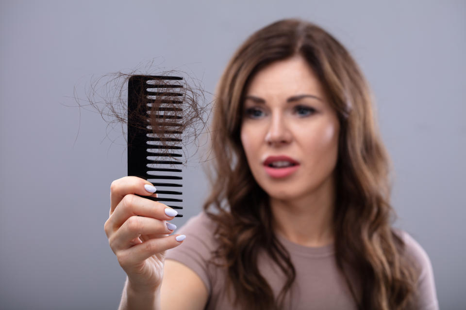 Woman looking worried at a comb with hair loss, reflecting parenting concerns