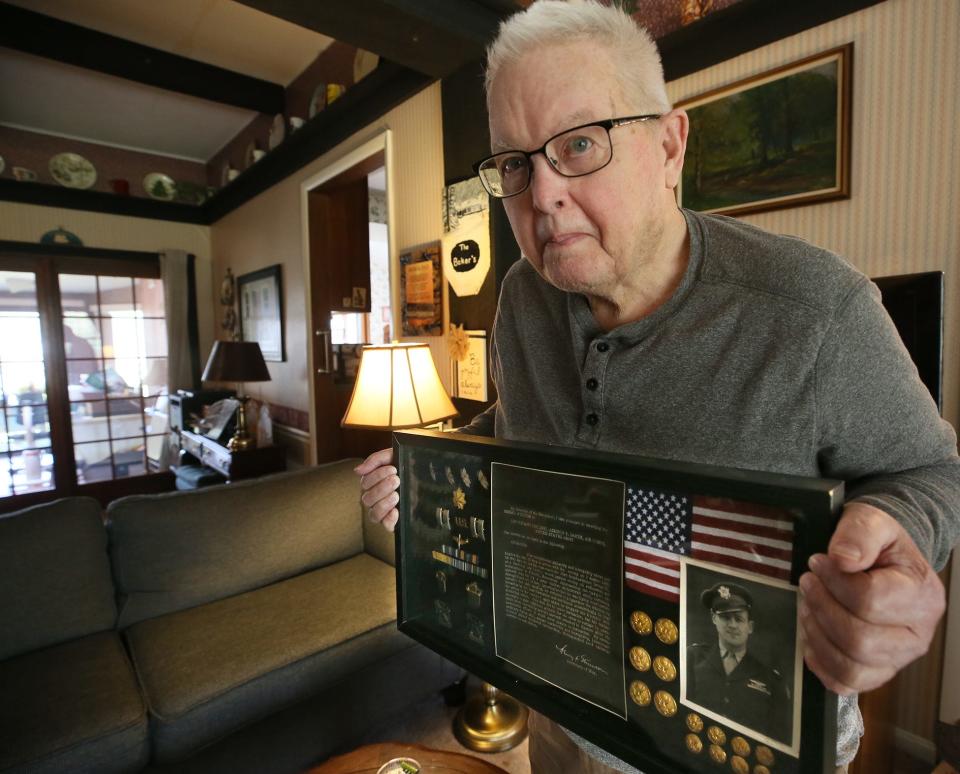 Dave Baker holds an awards display for his uncle Lt. Col. Addison Baker, whose plane was shot down in 1943 during World War II.