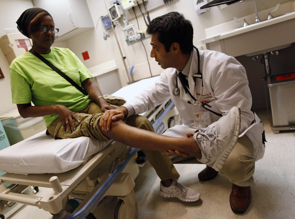 Patient Sharon Dawson Coates has her knee examined by Dr. Narang at University of Chicago Medicine Urgent Care Clinic in Chicago, June 28, 2012. A sharply divided U.S. Supreme Court on Thursday upheld the centerpiece of President Barack Obama's signature healthcare overhaul law that requires that most Americans get insurance by 2014 or pay a financial penalty. REUTERS/Jim Young (UNITED STATES - Tags: EDUCATION HEALTH POLITICS)