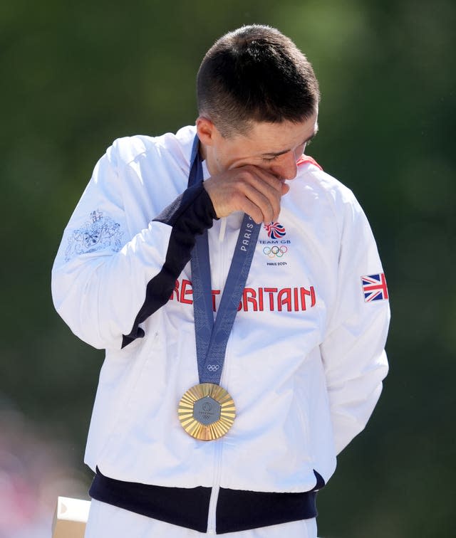 Great Britain’s Tom Pidcock wipes away a tear, wearing his gold medal