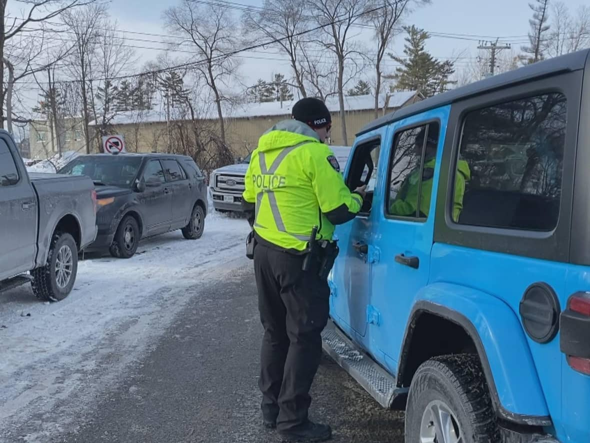 An Ottawa police officer speaks to a driver during a traffic blitz last Wednesday. Police say the number of people with expired licences has shot up ever since the Ontario government stopped sending out reminders. (Kimberley Molina/CBC - image credit)