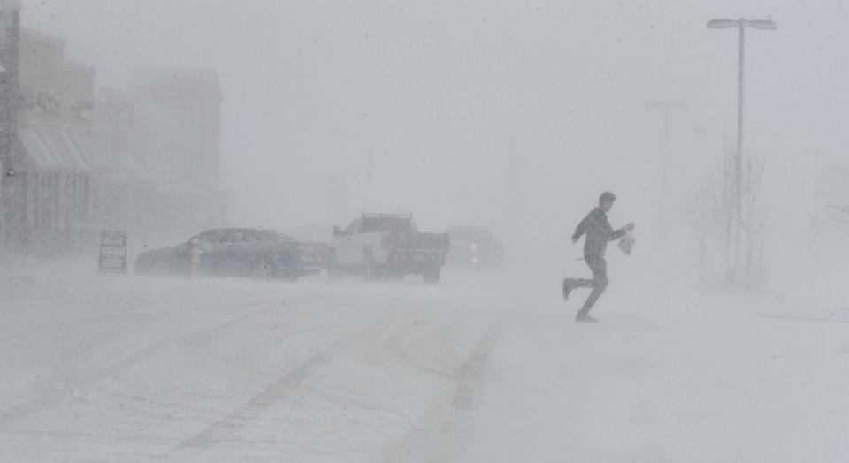 Clutching a bag of groceries a man sprints to his car as he leaves the Sprouts grocery store on North Gate Blvd. in Colorado Springs, Colo. At that time, the store was still open while a massive blizzard was moving through on Wednesday, March 13, 2019. Some of Colorado's busiest highways are closed as a raging storm brings heavy snow to a wide swath of the West and Midwest. Many schools and state offices were shut down Wednesday amid a blizzard expected to engulf parts of Colorado, Wyoming, Montana, Nebraska and South Dakota. (Jerilee Bennett/The Gazette via AP)