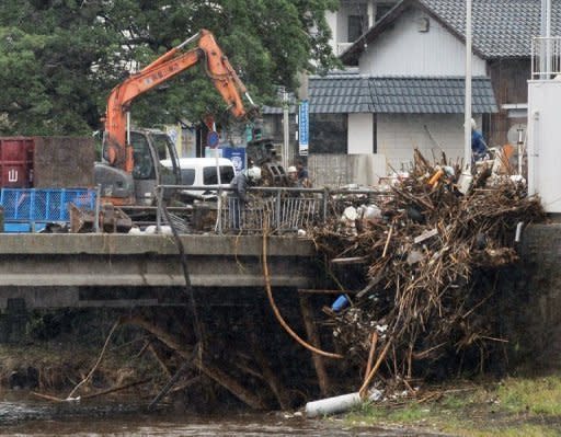 Workers remove debris from the railing of a bridge in Kumamoto prefecture, on Japan's southern island of Kyushu on July 13. Rainfall of up to 81.7 centimetres has been recorded in hardest-hit Aso, situated at the foot of a volcano, where at least 18 people were killed and four others were still missing