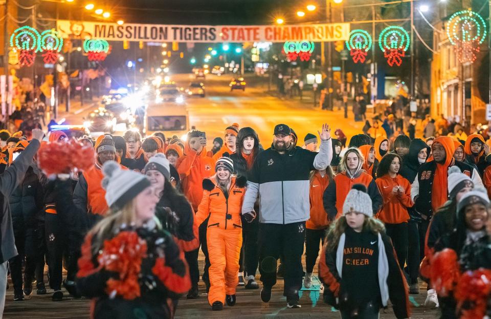 Tigers football head coach Nate Moore and his wife, Becca, march with the team through downtown Massillon Sunday night as the city celebrated the school's 2023 state football title.