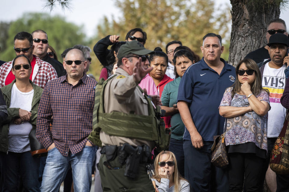 An officer instructs families as they wait to reunite with their children in Central Park following a shooting that injured several people at Saugus High School, Thursday, Nov. 14, 2019, in Santa Clarita, Calif. (Sarah Reingewirtz/The Orange County Register via AP)