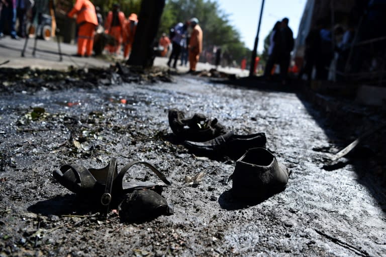 Footwear of victims is seen on the ground as Afghan residents inspect the site of a car bomb attack in western Kabul