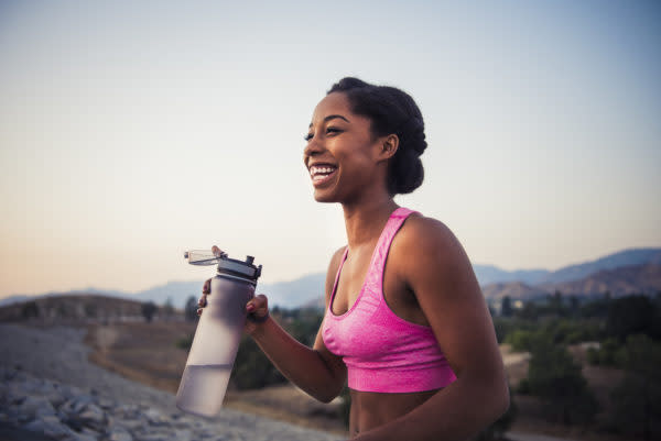 black woman wearing active gear and holding a water bottle