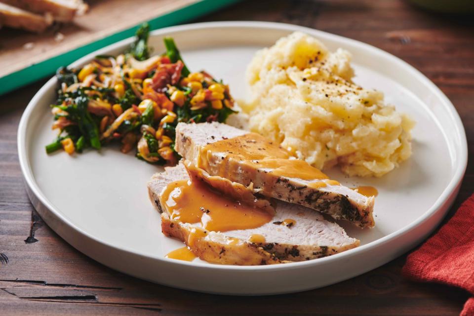 This May 2019 photo shows a plate of turkey, mash potatoes and gravy and a side of sauteed broccoli rabe, corn and onions with crispy bacon, on a table in New York. If you remember that the turkey breast will take less time to cook than the legs, and that you can get a head start on your gravy, Thanksgiving will be a whole lot less stressful. (Cheyenne Cohen/Katie Workman via AP)