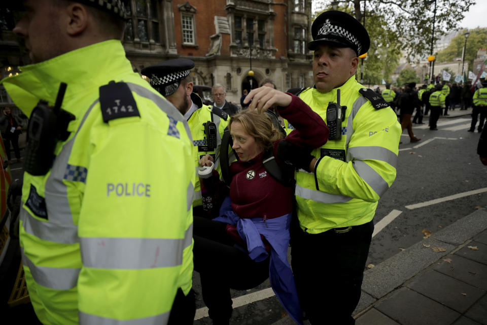 An Extinction Rebellion climate change protester is carried away by police after laying down and blocking the road on Millbank in London, Tuesday, Oct. 8, 2019. Hundreds of climate change activists camped out in central London on Tuesday during a second day of world protests by the Extinction Rebellion movement to demand more urgent actions to counter global warming. (AP Photo/Matt Dunham)