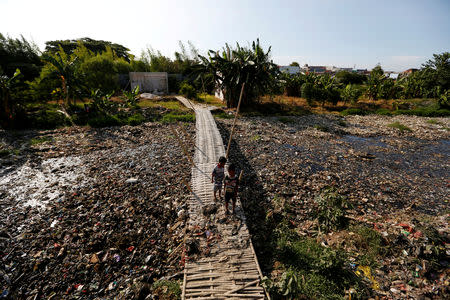 Children stand on a bridge near a river covered by rubbish in Bekasi, West Java province, Indonesia, January 7, 2019. REUTERS/Willy Kurniawan/Files