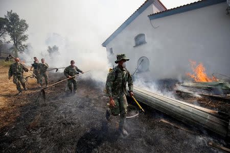 Soldiers help to put out a forest fire in the village of Capelo, near Gois, Portugal June 21, 2017. REUTERS/Rafael Marchante