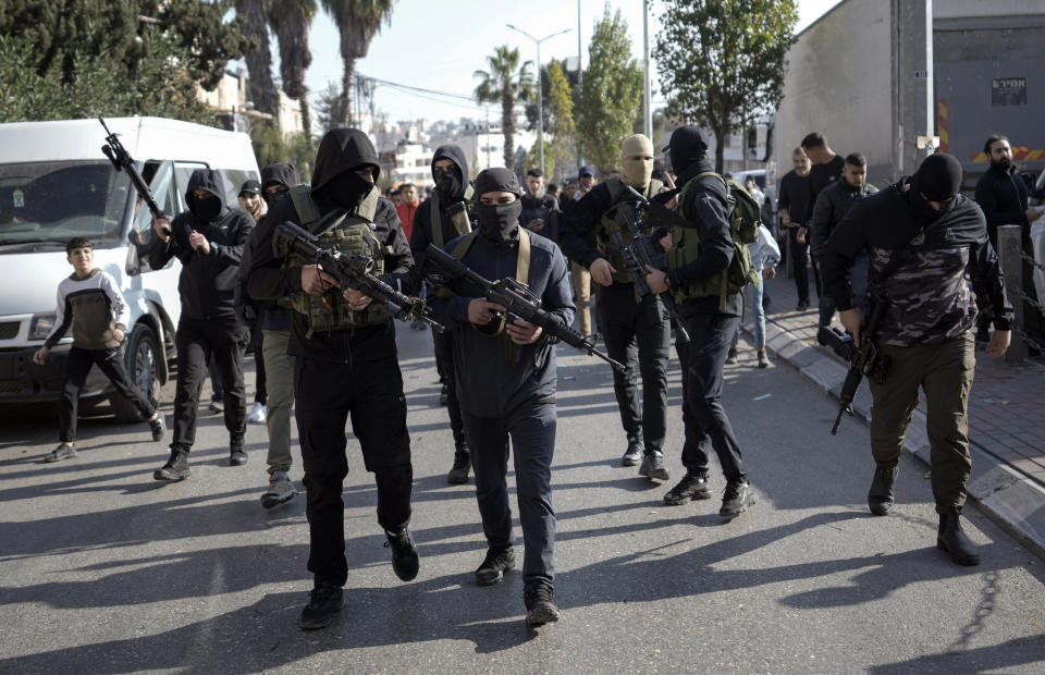 Masked Palestinian gunmen march during a protest, Tuesday, Dec. 20, 2022, in the West Bank city of Ramallah, after Palestinian prisoner Nasser Abu Hamid died of lung cancer in Israel. Abu Hamid was a former leader of the Al Aqsa Martyrs' Brigade, the armed wing of Palestinian President Mahmoud Abbas's Fatah party. He had been serving seven life sentences after being convicted in 2002 for involvement in the deaths of seven Israelis during the second Palestinian intifada, or uprising, against Israel's occupation in the early 2000s. (AP Photo/Majdi Mohammed)