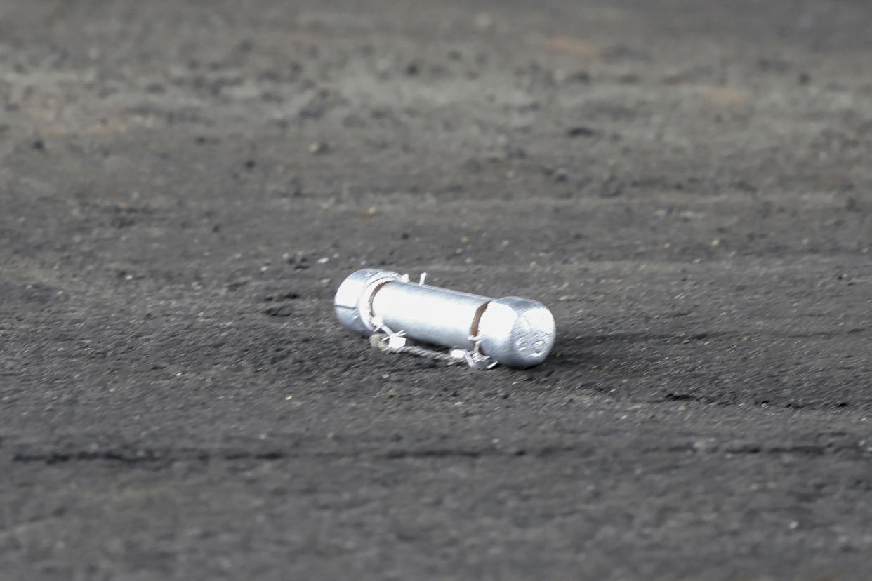 A suspicious object is seen on the ground where a suspect was arrested before Japanese Prime Minister Fumio Kishida was to begin his speech, at the Saikazaki port in Wakayama prefecture, western Japan, Saturday, April 15, 2023. Kishida was evacuated unharmed Saturday after someone threw an explosive device in his direction while he was campaigning at the fishing port in western Japan, officials said.(Kyodo News via AP)