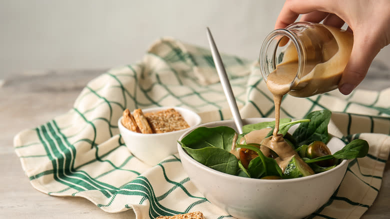 Hand pouring dressing on salad