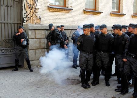 Policemen retreat from a smoke flare which was thrown by a protester during a rally against the laws to provide separatist-held regions with a special status near the Ukrainian parliament in Kiev, September 17, 2014. REUTERS/Valentyn Ogirenko