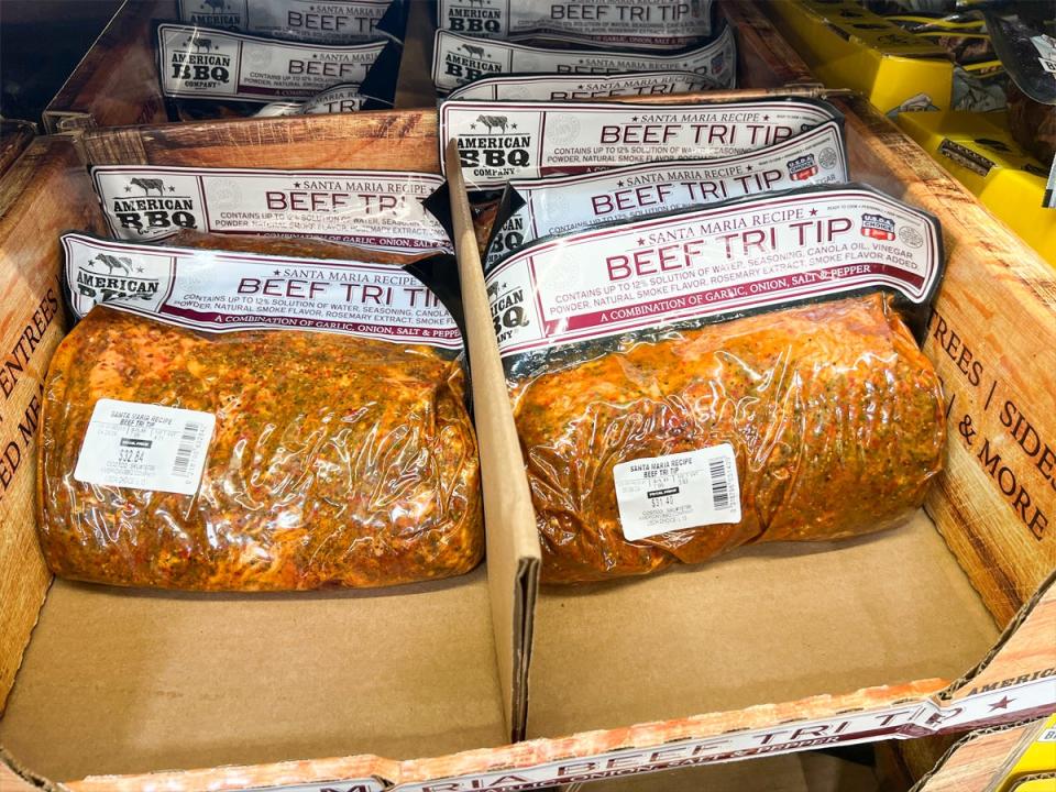 Clear plastic bags of beef tri tip with white labels and red lettering in cardboard boxes at Costco