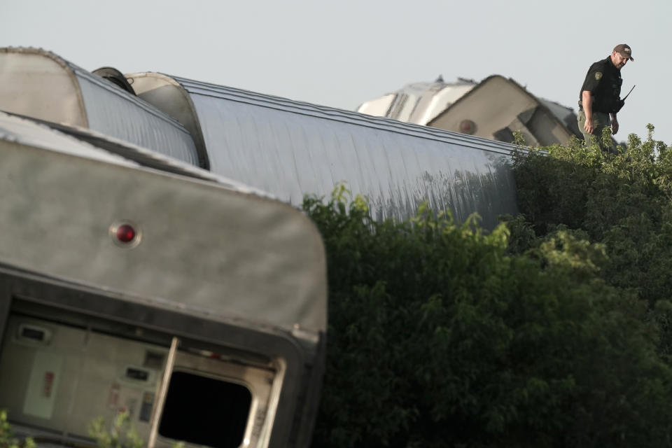 A law enforcement officer inspects the scene of an Amtrak train which derailed after striking a dump truck Monday, June 27, 2022, near Mendon, Mo. (AP Photo/Charlie Riedel)