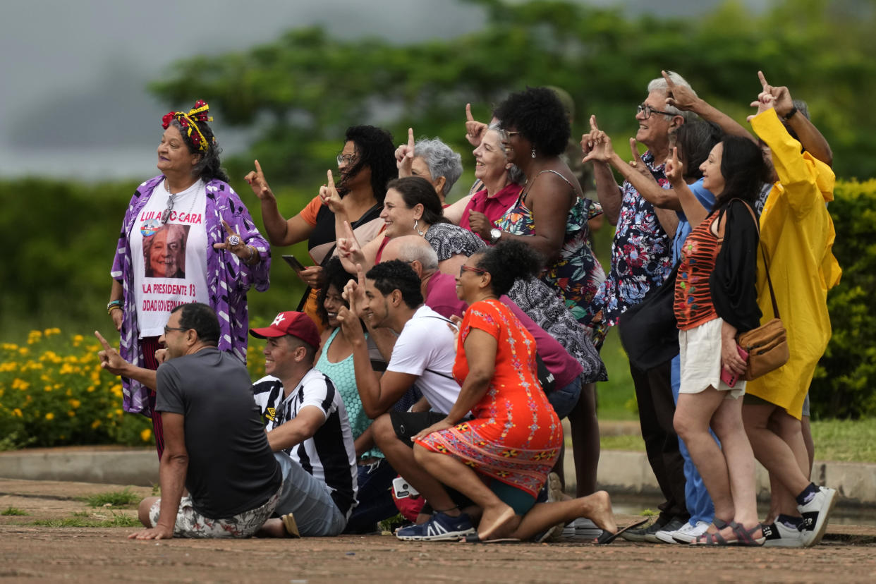 Shortly after supporters of outgoing President Jair Bolsonaro ended their vigil outside the official residence Alvorada Palace, supporters of incoming President-elect Luiz Inacio Lula da Silva arrived on the grounds, posing for photos flashing the "L" finger gesture for Lula, in Brasilia, Brazil, Friday, Dec. 30, 2022. Lula will be sworn-in on Jan. 1, 2023 as the country's new leader. (AP Photo/Eraldo Peres)