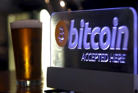 A beer poured for a customer sits on a bar next to a Bitcoin sign in central Sydney, Australia, September 29, 2015. REUTERS/David Gray