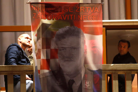 Bosnian Croats hang a flag displaying a portrait of General Slobodan Praljak and a message that reads "Your sacrifice will never be forgotten", as people pray and light candles for the convicted general, who killed himself seconds after the verdict in the U.N. war crimes tribunal, in Mostar, Bosnia and Herzegovina November 29, 2017. REUTERS/Dado Ruvic