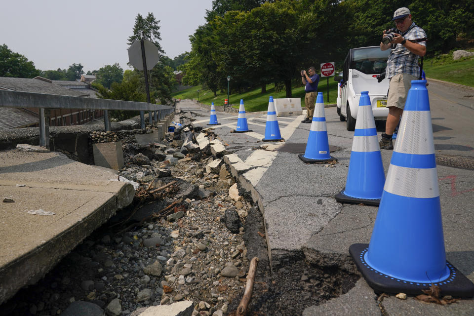 Members of the media look over a partially collapsed road on the campus of the United States Military Academy at West Point in Highland Falls, N.Y., Monday, July 17, 2023. Heavy rains are pounding an already saturated Northeast for the second time in a week, spurring another round of flash flooding, canceled airline flights and power outages. (AP Photo/Seth Wenig)