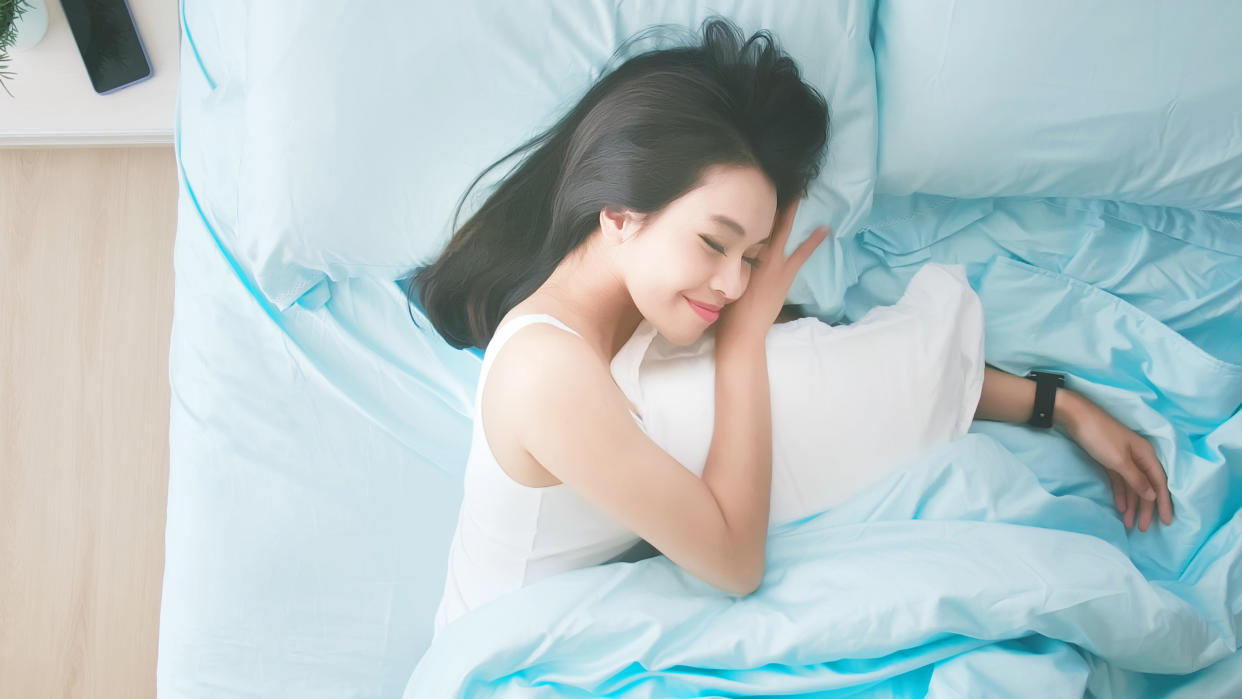  Woman asleep in bed wearing smartwatch. 