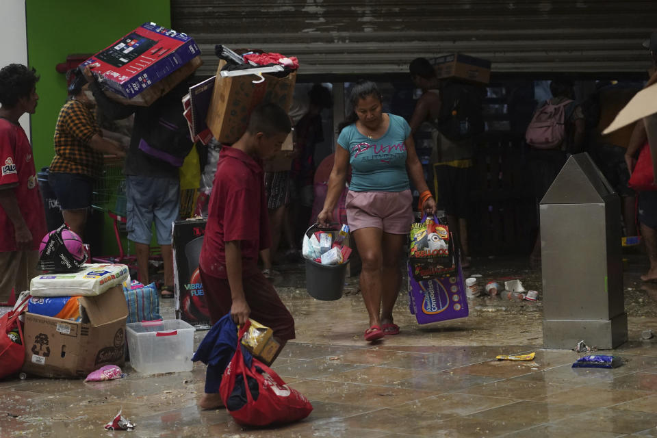 Varias personas toman productos de una tienda de comestibles luego del paso del huracán Otis por Acapulco, México, el 25 de octubre de 2023. (AP Foto/Marco Ugarte)