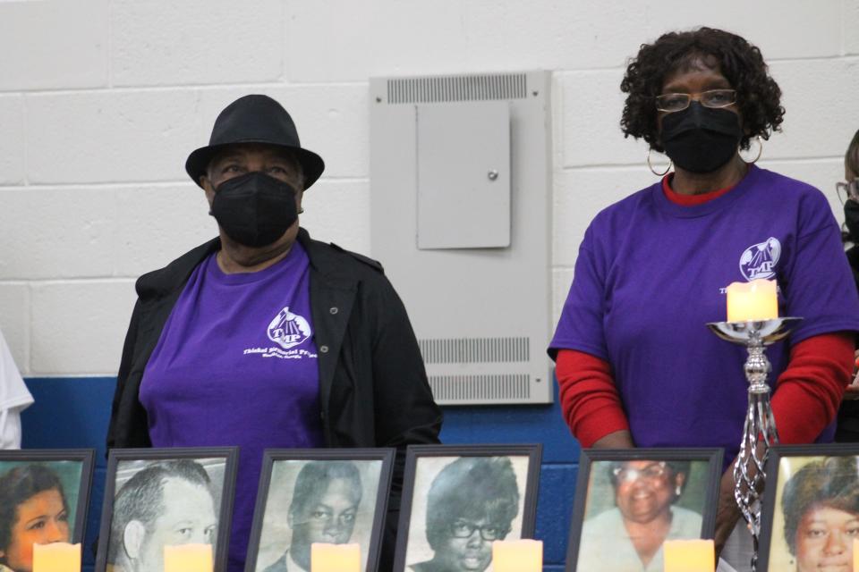 Survivors of the Feb. 3, 1971, explosion at the Thiokol plant in Woodbine, Georgia, stand behind the pictures of the victims of the tragedy at the 52nd commemoration ceremony for the Thiokol plant explosion in Woodbine on Feb. 3, 2023.