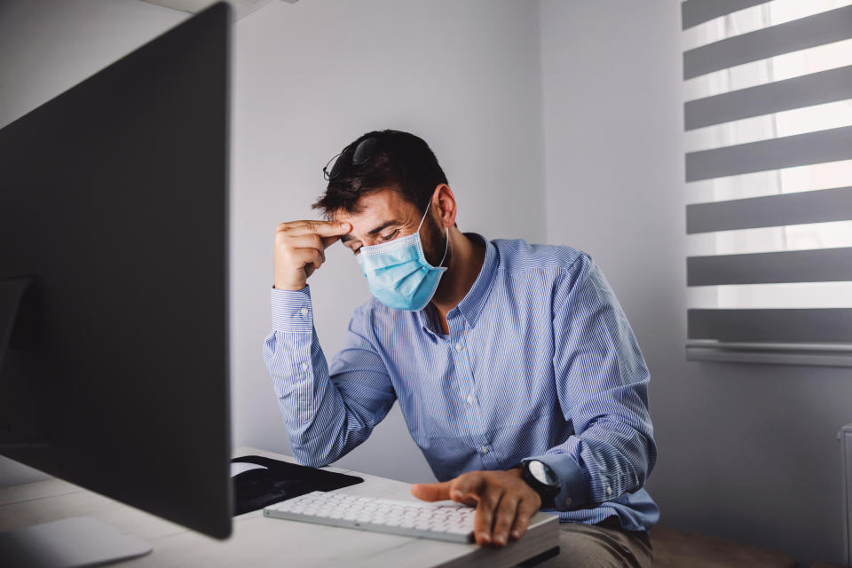 A worker in a surgical mask at his keyboard. 