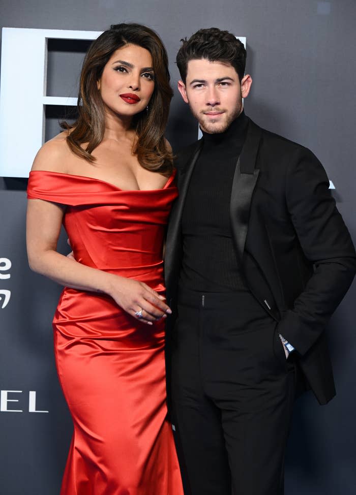 Priyanka Chopra in a satin off-shoulder dress and Nick Jonas pose together in a sophisticated suit