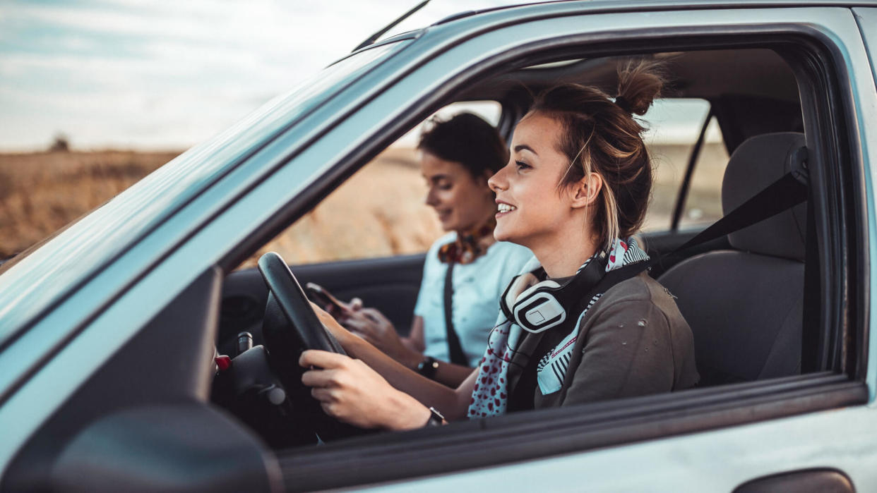 Beautiful twin sisters driving a car and enjoying summer road trip.