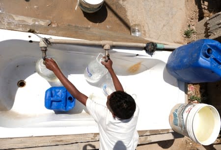 A Libyan boy displaced from the town of Tawergha fills containers with water at a displaced camp in Benghazi