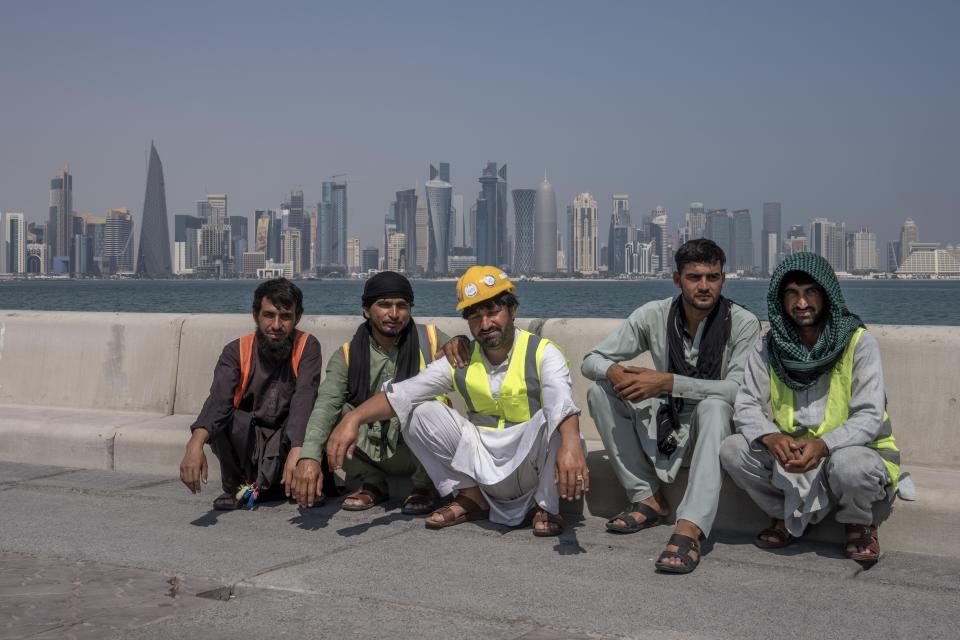 Pakistani migrant laborers pose for a photograph, as they take a break, on the corniche, overlooking the skyline of Doha, Qatar, Wednesday, Oct. 19, 2022. One of the world’s biggest sporting events has thrown an uncomfortable spotlight on Qatar’s labor system, which links workers’ visas to employers and keeps wages low for workers toiling in difficult conditions. (AP Photo/Nariman El-Mofty)