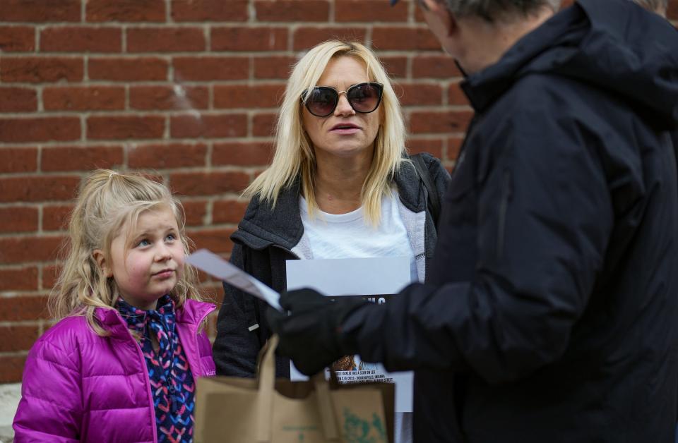 Breanne Rice and Daisy Rice, 7, hand out fliers to passersby during a prayer vigil for 2-year-old Oaklee Snow on Monday, April 17, 2023, outside of City Market in Indianapolis. In January, Snow was taken from her father's home in Oklahoma without his consent by her mother, Madison Marshall. Snow was last seen by a witness in Indianapolis in February, but remains missing. 