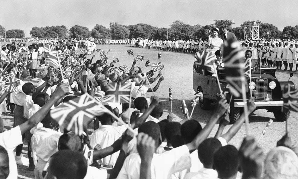 Thousands of flag-waving youngsters cheer as Queen Elizabeth II and the her husband Prince Philip, Duke of Edinburgh, ride through the Kaduna racecourse in Northern Nigeria on Feb. 2, 1956. (AP Photo, File)