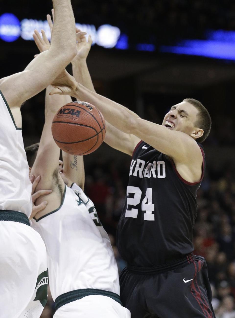 Harvard's Jonah Travis (24) loses the ball as he runs into Michigan State's Kenny Kaminski in the first half during the third round of the NCAA men's college basketball tournament in Spokane, Wash., Saturday, March 22, 2014. (AP Photo/Elaine Thompson)