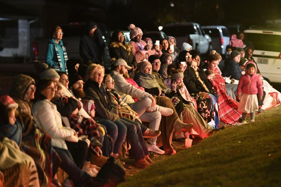 People wrap up against the cold and sit curbside during a Live Outdoor Christmas Nativity Pageant: The Story of Christmas outside 904 Princeton Place in Northport Tuesday, Dec. 19, 2023.