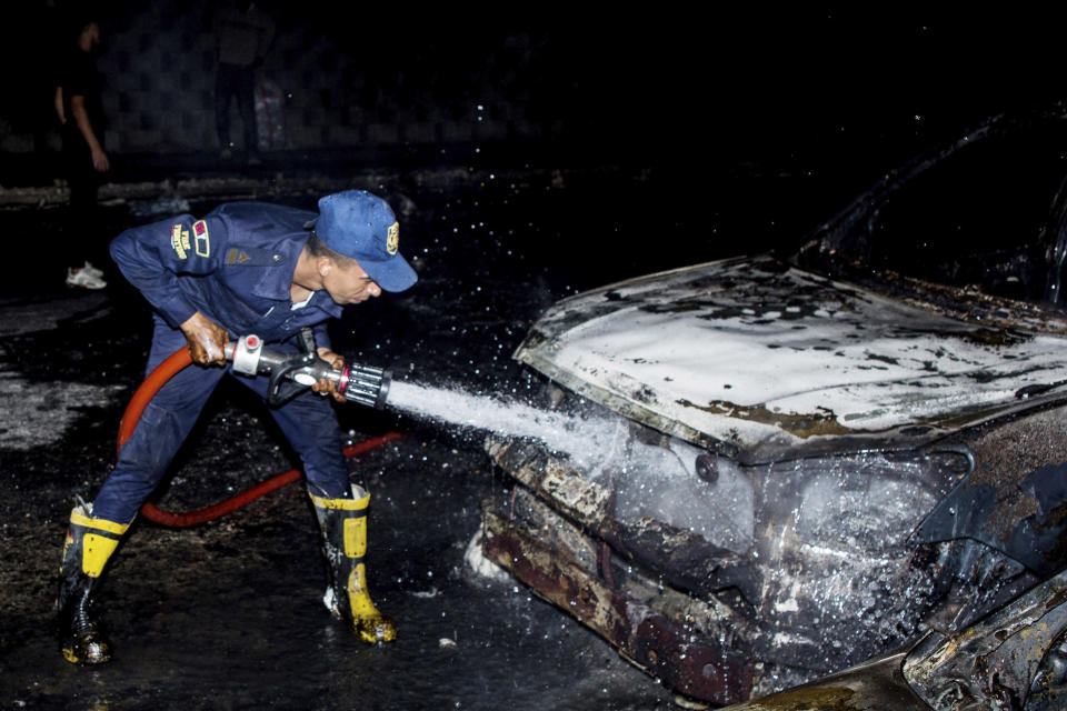 A firefighter hoses down burned vehicles following a fire that broke out in the Shuqair-Mostorod crude oil pipeline, on the Cairo-Ismailia road, in Egypt, Tuesday, July 14, 2020. A ruptured crude oil pipeline set off a monstrous blaze on a desert highway in Egypt on Tuesday, injuring at least 17 people, local authorities said. (AP Photo/Alaa Ahmed)