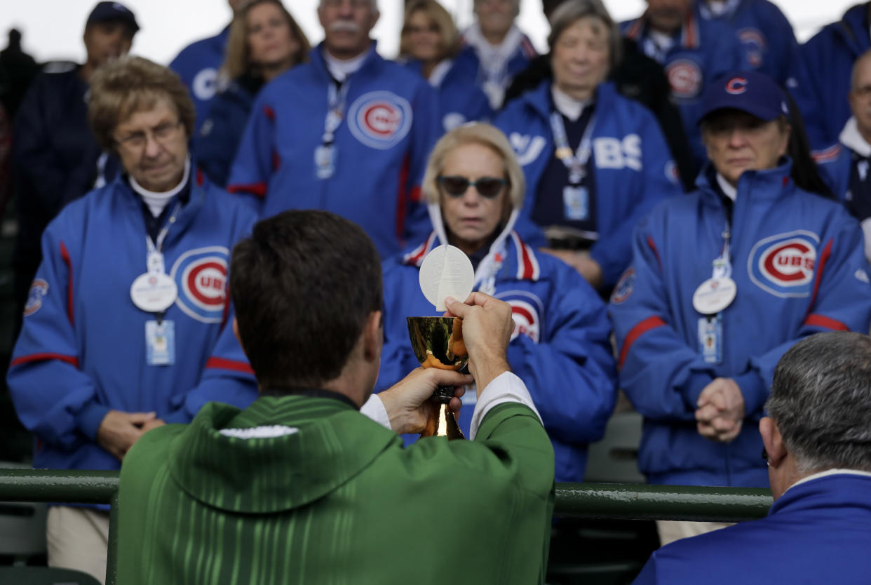 FILE - Rev. Burke Masters conducts an outdoor Mass in the Wrigley Field stands prior to Game 5 of the Major League Baseball World Series between the Cleveland Indians and the Chicago Cubs Sunday, Oct. 30, 2016, in Chicago. A poll by The Associated Press and the NORC Center for Public Affairs Research conducted Sept. 9-12, 2022, finds that about 3 in 10 Americans say they feel God plays a role in determining which team goes home the victor. (AP Photo/Charlie Riedel, File)